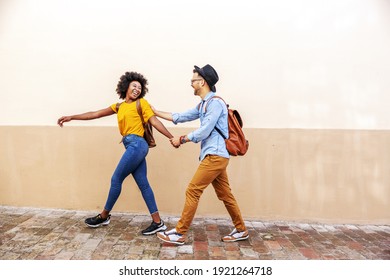 Young attractive happy multiracial couple standing outdoors on a beautiful sunny day flirting on the street while walking. - Powered by Shutterstock