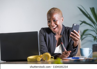 Young Attractive And Happy Successful Black Afro American Woman In Business Jacket Working Cheerful At Office Laptop Taking Notes Using Mobile Phone Satisfied In Work Success Concept