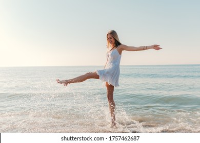 young attractive happy woman dancing turning around by sea beach sunny summer fashion style in white dress vacation - Powered by Shutterstock