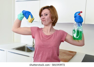 young attractive and happy woman with red hair in rubber washing gloves holding cleaning spray bottle and scourer smiling proud and positive in housework and domestic work concept