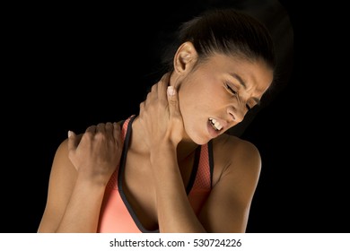 Young Attractive Hispanic Fitness Woman Touching And Grabbing Her Neck And Upper Back Suffering Cervical Pain Isolated On Black Background In Sport Injury And Body Health Care Concept