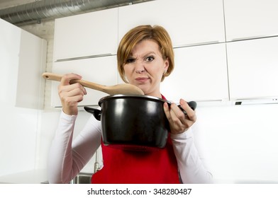 Young Attractive Home Cook Woman At Domestic Kitchen Holding Cooking Pot And Spoon Tasting Her Soup In A Funny  Disgusting Bad Taste Face Expression Because Of Unsuccessful Stew