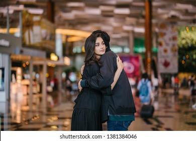 A Young And Attractive Indian Asian Woman Is Hugging Her Boyfriend In A Futuristic Airport During The Day. She Looks Sad At The Prospect Of Missing Him As He Goes Out Of Country. 