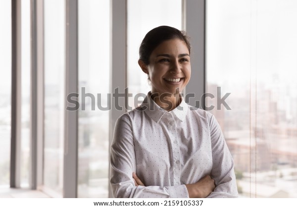 Young attractive Indian businesswoman smile pose\
in company office. Female intern or student feels happy photoshoot\
indoor. Ambitious employee, teacher, professional occupation person\
portrait concept