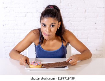 Young Attractive Latin Woman Sitting At Table About To Eat Chocolate And Doughnuts Looking Excited And Happy In No More Diet, Sugar And Chunky Unhealthy Food Concept.