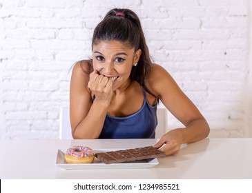 Young Attractive Latin Woman Sitting At Table About To Eat Chocolate And Doughnuts Looking Excited And Happy In No More Diet, Sugar And Chunky Unhealthy Food Concept.