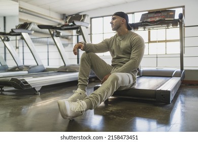 A Young Attractive Male In A Sweat Suit Posing Sitting On A Treadmill