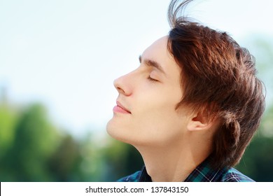 Young Attractive Man Breathing Fresh Air Outdoors Showing His Face To The Wind