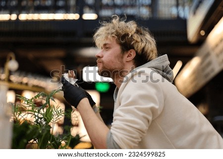 Young attractive man enjoying a hot dog in a street food restaurant.
