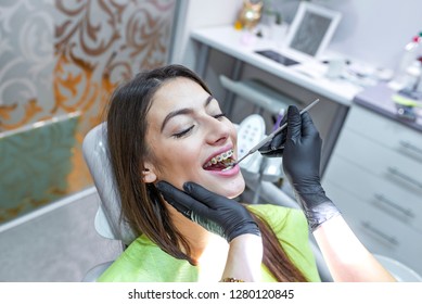 Young attractive man on a review of the doctor dentist. Beautiful girl with braces smiles in dentistry. Dentist and patient in dentist office  - Powered by Shutterstock