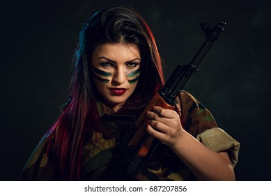 Young Attractive Military Woman With Face Paint In War Paint Holding Rifle And Looking At Camera.