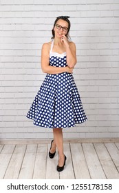 Young Attractive Pin Up Girl In A Vintage 1950's Dress Petticoat Dress Posing In Front Of A Stone Wall