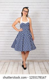 Young Attractive Pin Up Girl In A Vintage 1950's Dress Petticoat Dress Posing In Front Of A Stone Wall