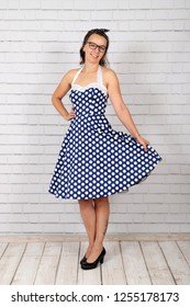 Young Attractive Pin Up Girl In A Vintage 1950's Dress Petticoat Dress Posing In Front Of A Stone Wall