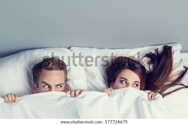 Young Attractive Playfull Couple Peeping Bedsheet Stock