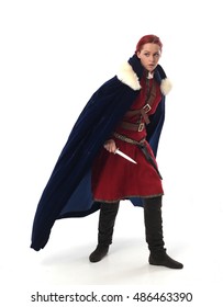 Young And Attractive Red Haired  Female Warrior,  Wearing A Red Medieval Tunic And Leather Armour.  Isolated On A White 
