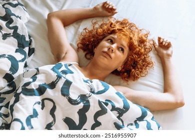 young attractive redhead curly woman waking up with pleasure stretching lying in bed. enjoying rest lazily lying down - Powered by Shutterstock