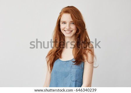 Young attractive redhead girl smiling looking at camera.