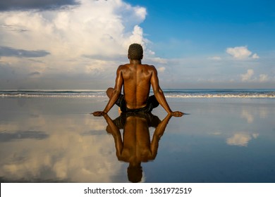 young attractive and relaxed black afro American man with fit body and muscular back sitting on beach sand enjoying beautiful view thinking and meditating free contemplating the sea