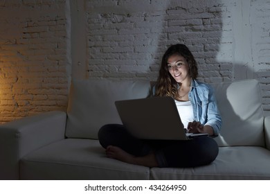 Young Attractive And Relaxed Woman At Home Smiling Happy On Sofa Couch Using Laptop Computer In Dark Evening Light Enjoying Watching On Line Movie Or Addicted To Internet Social Network