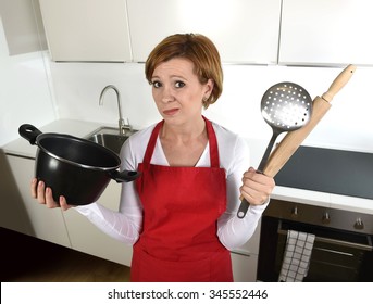 Young Attractive Rookie Home Cook Woman In Red Apron At Home Kitchen Holding Cooking Pan And Rolling Pin Sad In Stress Confused And Helpless In Lifestyle And Cooking Mess