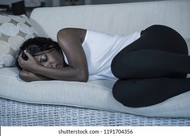 young attractive and sad black African American woman lying depressed at home sofa couch feeling anxious and frustrated suffering depression problem and anxiety crisis or terrible headache