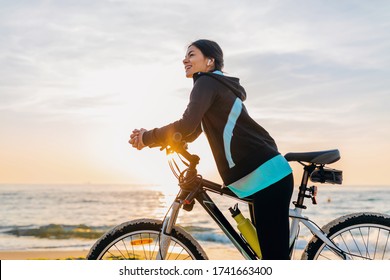 Young Attractive Slim Woman Riding Bicycle, Sport On Morning Sunrise Summer Beach In Sports Fitness Wear, Active Healthy Lifestyle, Smiling Happy Having Fun