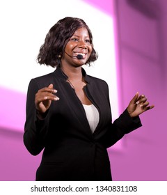 Young Attractive And Successful Black African American Business Woman With Headset Speaking In Auditorium At Corporate Training Event Or Seminar Giving Motivation And Success Coaching Conference