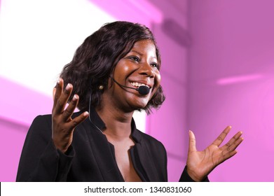 Young Attractive And Successful Black Afro American Business Woman With Headset Speaking In Auditorium At Corporate Training Event Or Seminar Giving Motivation And Success Coaching Conference