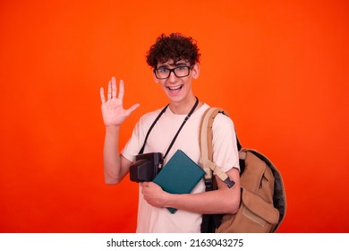 Young attractive tourist with a backpack. Orange background.