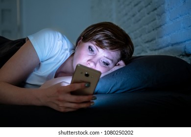 Young attractive woman awake late at night using smart phone lying in bed in a dark bedroom. Using mobile for chatting and sending messages in internet addiction, mobile abuse and insomnia concept - Shutterstock ID 1080250202