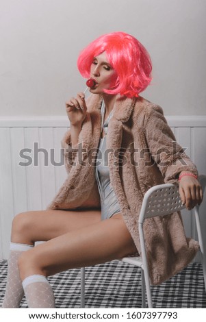 Young attractive woman in a bright pink wig, golf and faux fur coat. Bright fashion or party look.