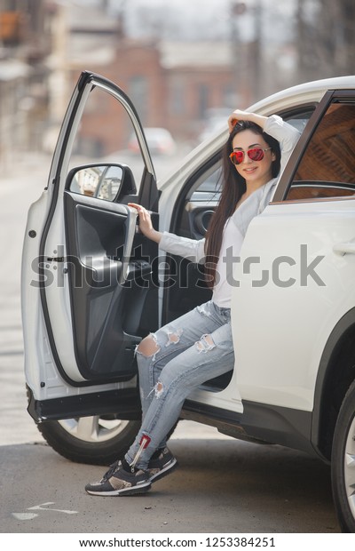 Young attractive\
woman in the car. Woman drive an auto. Close up portrait of\
beautiful woman outdoors. Urban\
lady.