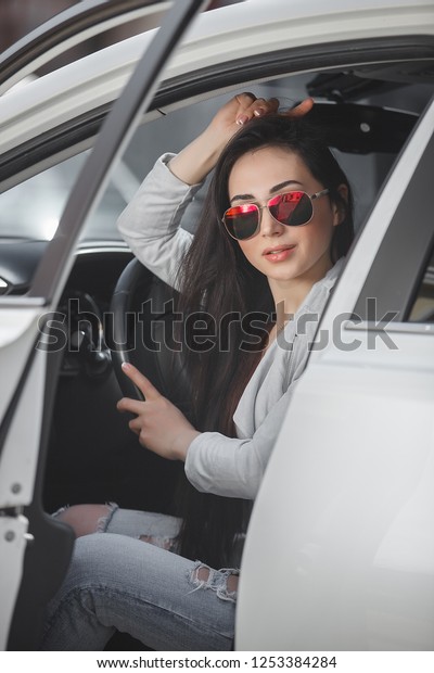 Young attractive\
woman in the car. Woman drive an auto. Close up portrait of\
beautiful woman outdoors. Urban\
lady.