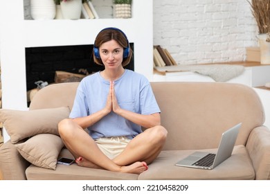 Young Attractive Woman Doing Yoga On The Sofa At Home. Stressful Day And Calm Down Concept	