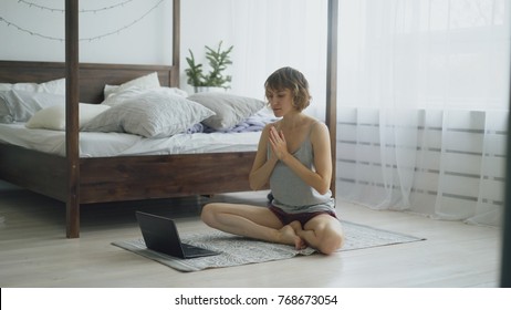 Young Attractive Woman Doing Yoga Exercise And Watching Tutorial Lesson On Laptop Computer At Home