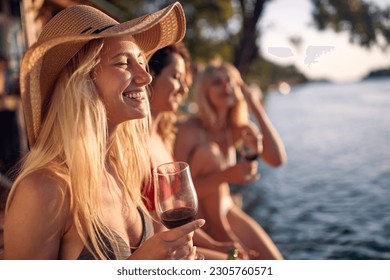 Young attractive woman drink wine on a dock by the water during the summer sunny day - Powered by Shutterstock