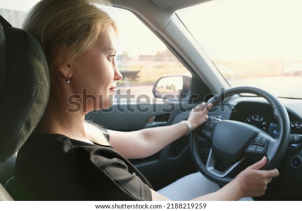 Young\
attractive woman drives a car. Profile photo of a beautiful blonde\
woman with long hair. Woman in a car while\
driving.