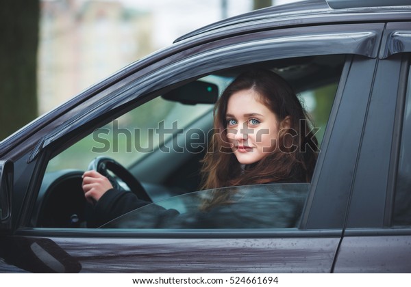 Young attractive\
woman driving the car in\
rain