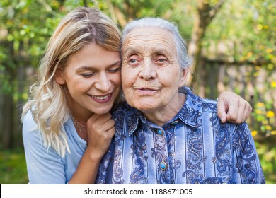 Junge attraktive Frauen umarmen alte Großmutter draußen. Weibliche Generationen - Liebe