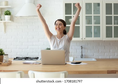 Young attractive woman exulting using calculator and laptop for calculating finance rates looking at screen. Successful girl happy hands up accounting with check credit analytic for mortgage payment.