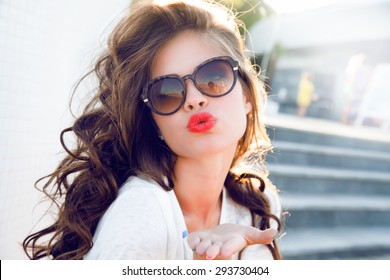 Young attractive woman face over isolated white background,send kiss,with red lips,amazing woman,hairstyle after salon,beauty face,party make-up,summer accessories,perfect bronze tan skin,lovely face