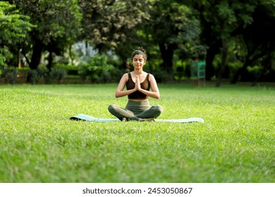 Young attractive woman in fitness wear sitting cross legged in the park with hands on her knees and meditating
 - Powered by Shutterstock