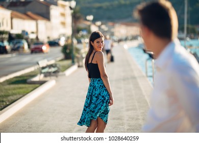 Young attractive woman flirting with a man on the street.Flirty smiling woman looking back on a handsome man.Female attraction.Love at first sight.Meeting ex boyfriend - Shutterstock ID 1028640259