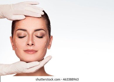 Young Attractive Woman Getting Spa Treatment. Beautiful Girl Receiving Massage Face. Anti Aging Treatment And Plastic Surgery Concept. Eyes Closed With Serene Expression And White Arrows Over Face