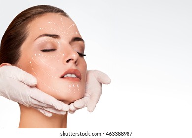 Young Attractive Woman Getting Spa Treatment. Beautiful Girl Receiving Massage Face. Anti Aging Treatment And Plastic Surgery Concept. Eyes Closed With Serene Expression And White Arrows Over Face