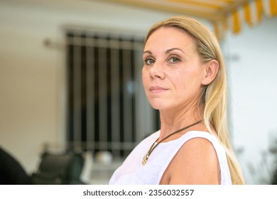 Young attractive woman in her forties looking at the camera with a friendly smile and sitting on the terrace