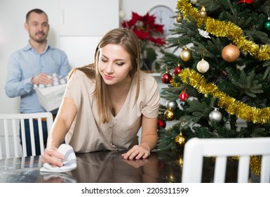 Young Attractive Woman With Her Husband Cleaning House Before Christmas Celebration, Wiping Table