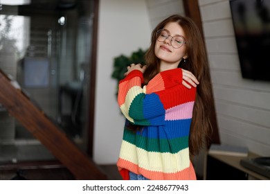 Young attractive woman hugging herself in a home interior, dressed in a warm sweater. - Shutterstock ID 2248677943