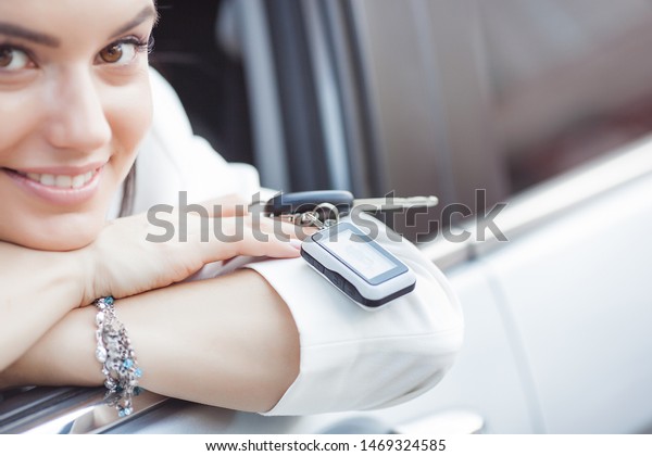 Young attractive woman just bought a new\
car. female holding keys from new\
automobile.